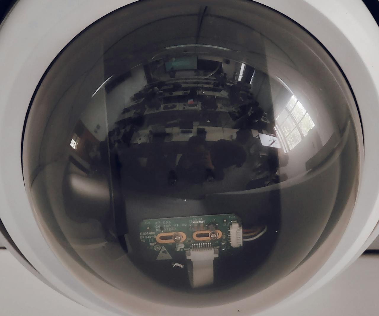 A close view of a surveillance dome camera reflecting an indoor setting.